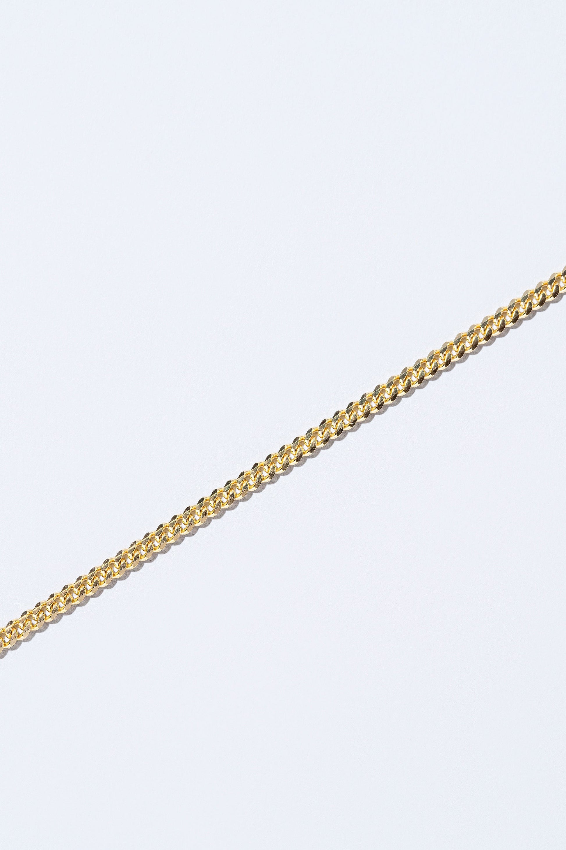 Closeup details of the 3.4mm Curb Chain Necklace on light color background.