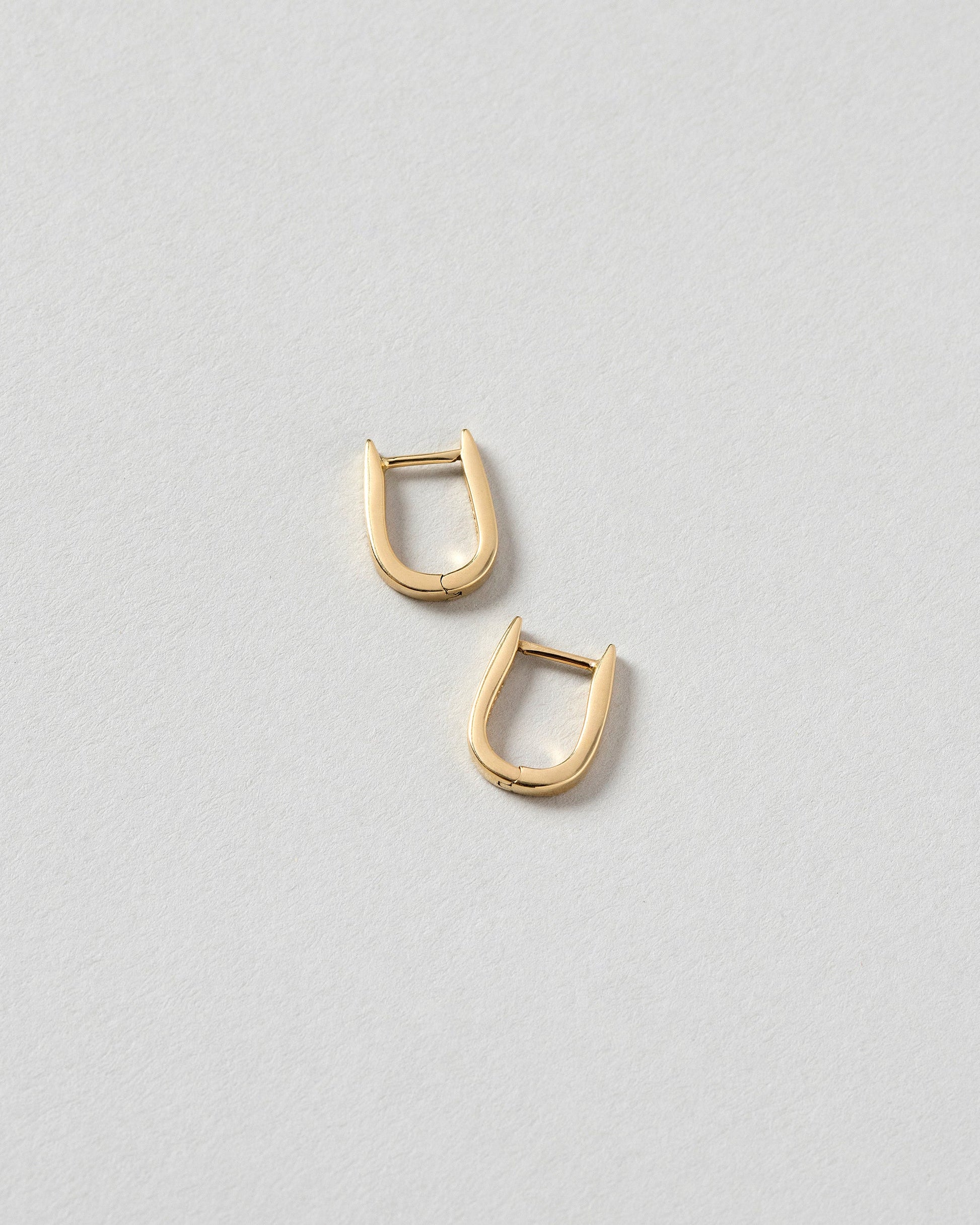 Poppy Flower Bud Huggie Hoop Earrings on light color background.