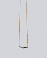 Sapphire & White Diamond Crescent Necklace on light color background.