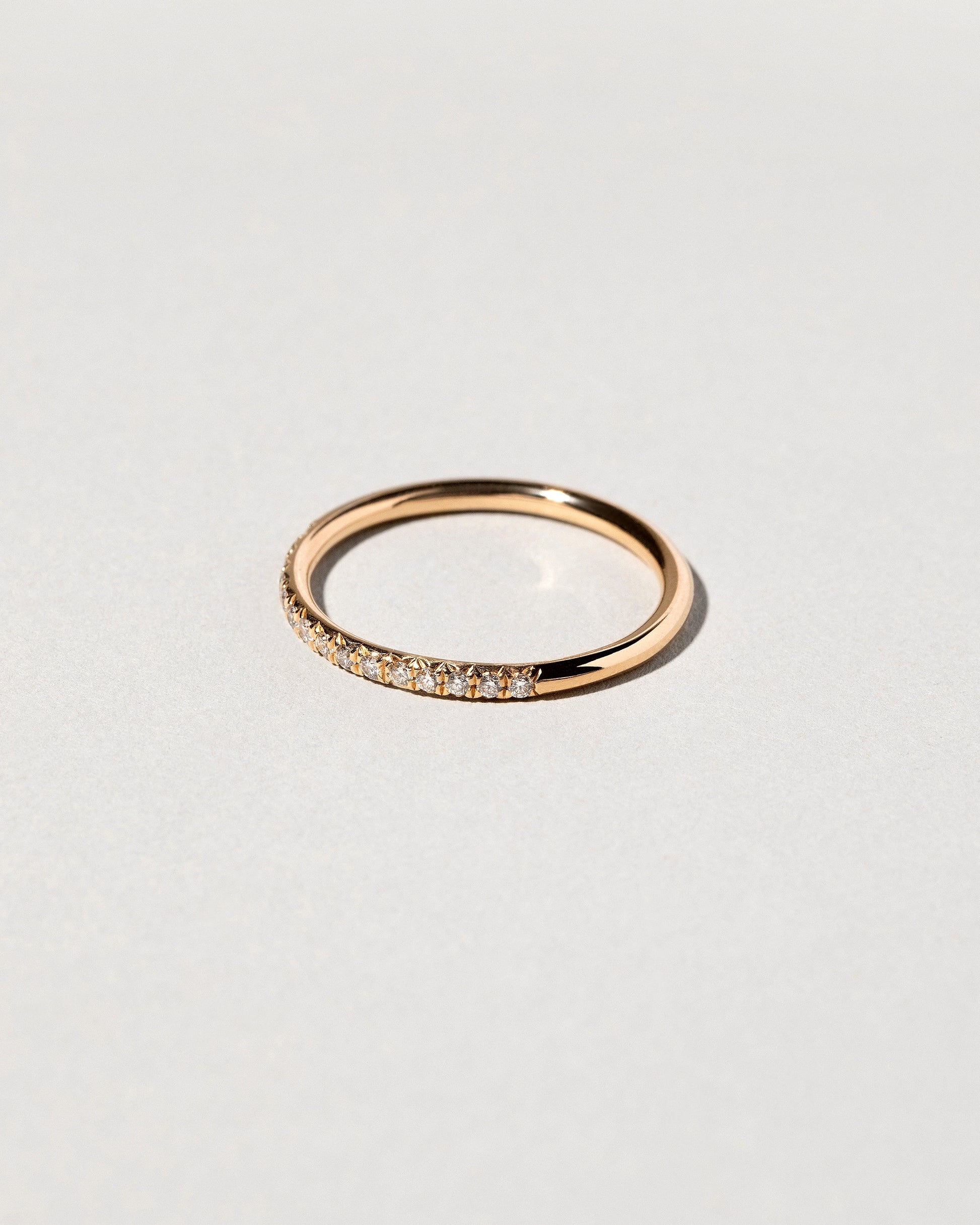 Closeup details of the Gold White Diamond Sapphire Fifteen Stone Dot Band on light color background.