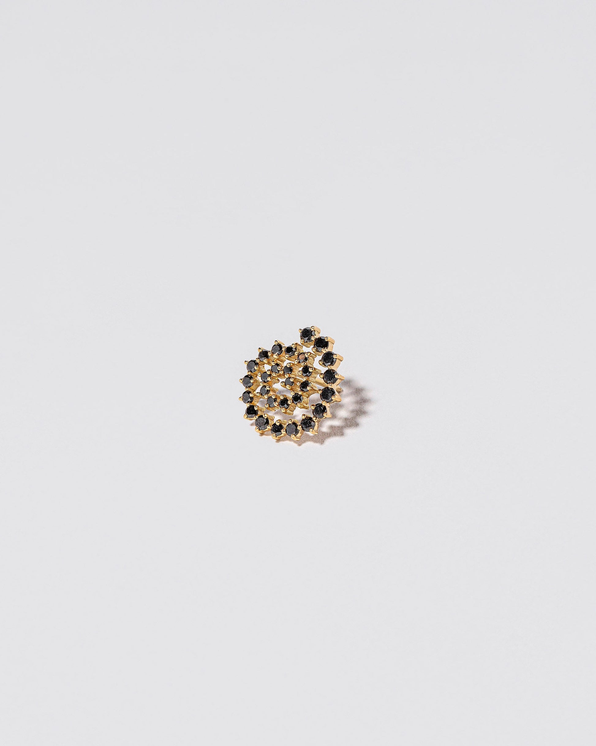 Closeup details of the Full Black Diamond Left Spiral Stud Earring Single on light color background.