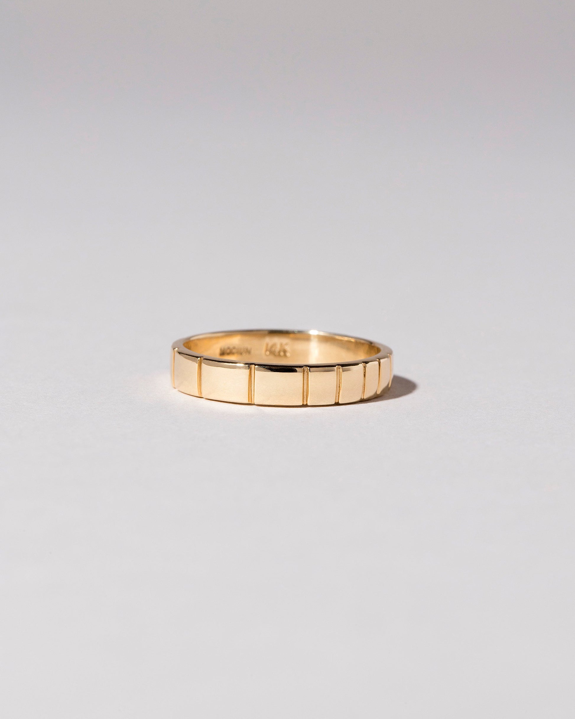 View from the side of the Gold 3mm Etched Lines Band on light color background.